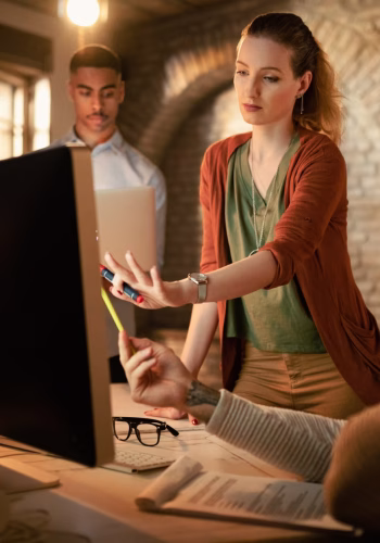 young-businesswoman-her-colleagues-brainstorming-while-using-desktop-pc-office-scaled.avif